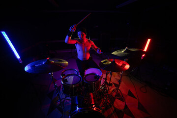Fototapeta premium Drummer playing live music with colorful stage lighting