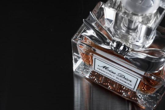 Stockholm, Sweden - January 25, 2026: Angled close-up of Miss Dior Absolutely Blooming perfume bottle with a metallic bow cap, set on a glossy black surface, emphasizing luxury, detail, and reflection