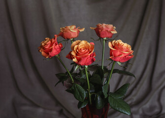 A bouquet of red roses in a glass vase on a dark background