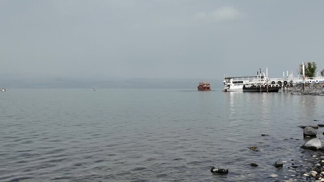 tourist boat on the Sea of Galilee lake or Kineret in northern Israel leaving port on an overcast winter day