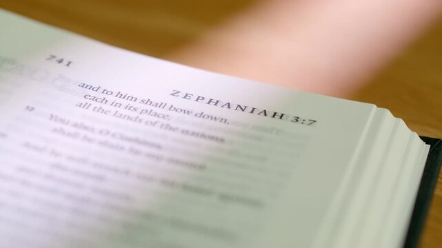 Bible Habakkuk and Zephaniah pages turn during a close up study of holy scripture. A detailed shot of flipping white paper from the end of Habakkuk to the start of Zephaniah in a modern Bible.