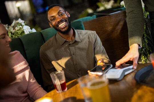 Group of people at a cafe using smartphones for contactless payment, showing modern digital transactions, convenience, and casual dining experience.