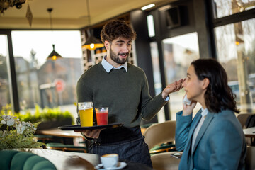 Waiter gently comforting a young woman who is upset in a restaurant, showing empathy and attentive...