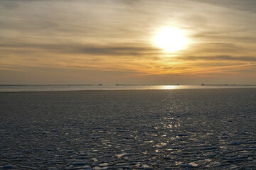 Fototapeta premium Golden winter sunset over frozen Baltic Sea with shimmering ice and calm horizon in Liepaja, Latvia