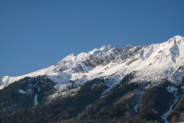 Obraz premium Snow-covered Nordkette mountains above Innsbruck, Austria, winter alpine panorama with clear blue sky and copy space