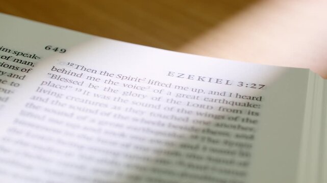 Bible Ezekiel 3 white pages turning book holy scripture close up. Extreme detailed shot of flipping paper in the Old Testament prophetic book about vision and watchman in a modern study.