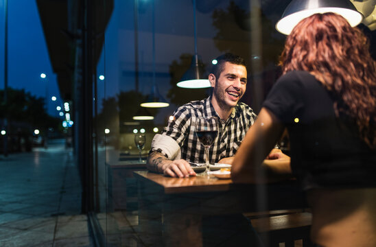 Couple in restaurant having dinner and drinking wine behind the window glass, Jaen, Spain.