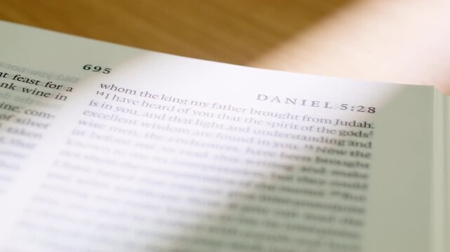 Bible Daniel 5 white pages turning book holy scripture close up. Extreme detailed shot of flipping paper in the Old Testament prophecy book about the writing on the wall and divine judgment.