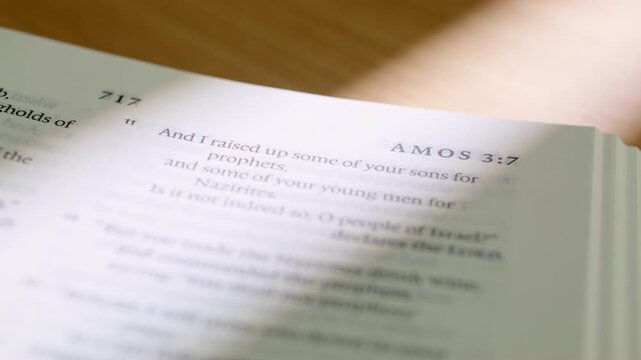 Bible Amos book pages turn during a close up study of holy scripture. A detailed shot of flipping white paper in the Old Testament book focused on justice, righteousness, and prophecy.