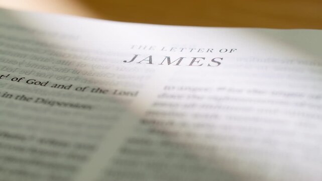 Bible book pages flipping to James letter. Turning pages of the New Testament letter regarding practical faith, wisdom, and good works. 4K close up shot for religious study and scripture reading.