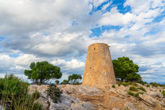 Scenic view of Torre Nova des Cap Vermell, an ancient stone watchtower on coast of Mallorca, Spain, with Mediterranean Sea, cliffs, and blue sky.