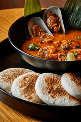 Traditional Thai Tom Yum Goong soup with mussels, shrimp, and toasted pita bread.