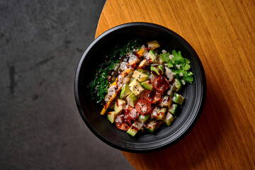 Fresh healthy poke bowl with avocado, mango, seaweed, and cherry tomatoes.