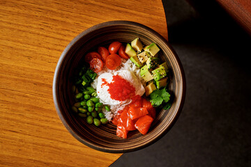 Fresh salmon poke bowl with poached egg, avocado, and edamame.