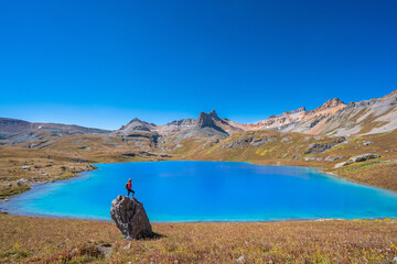 A woman hiker viewing a beautiful alpine lake in Colorado's San Juan mountains