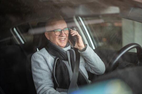 Mature man talking on smartphone in car