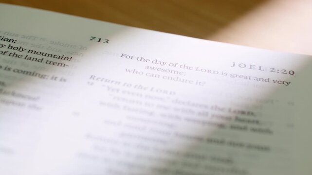 Bible Joel 2 book pages turn during a close up study of holy scripture. A detailed shot of white paper flipping through the Old Testament prophecy regarding the Day of the Lord and restoration.