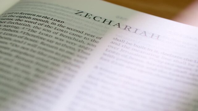 Bible Zechariah book pages turn during a close up study of holy scripture. A detailed shot of flipping through white paper in the Old Testament prophetic book of visions and messianic hope.