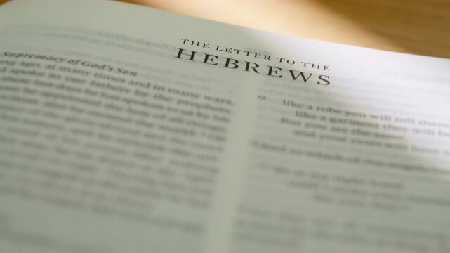 Bible pages flipping to Hebrews book. Turning pages of the New Testament letter regarding the high priesthood of Jesus, faith, and the better covenant. 4K close up shot for religious study.