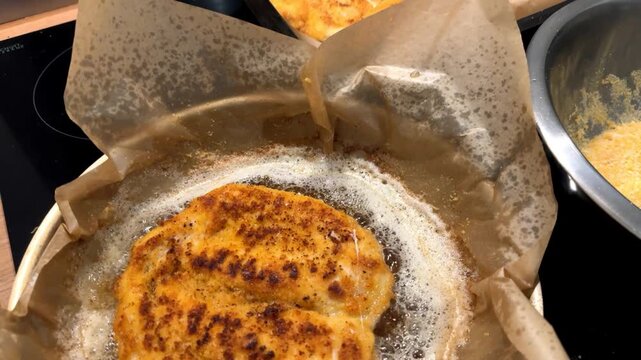 Meat being fried in a frying pan. Top view. Breaded meat in bubbling oil. Homemade dinner.