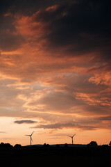 Modern Wind Turbines Silhouetted Against a Vibrant Sunset Sky, Renewable Energy Park in Rural Landscape Under Intense Evening Light