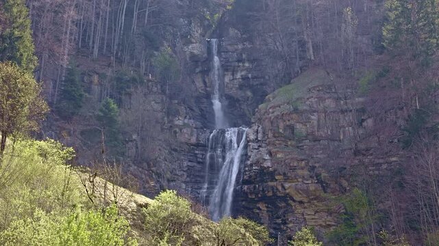 A scenic multi-tiered waterfall on a mountain stream dropping from steep slopes into the valley. Diesbachfall waterfall, canton Glarus, Switzerland.