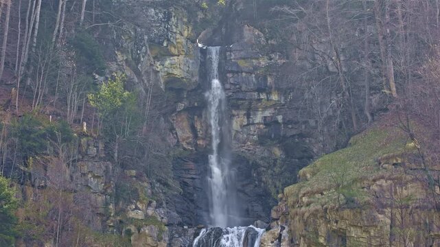 A scenic multi-tiered waterfall on a mountain stream dropping from steep slopes into the valley. Diesbachfall waterfall, canton Glarus, Switzerland.