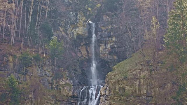 A scenic multi-tiered waterfall on a mountain stream dropping from steep slopes into the valley. Diesbachfall waterfall, canton Glarus, Switzerland.