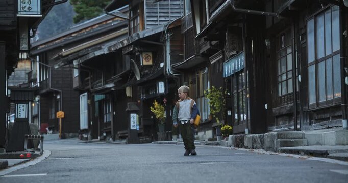 Little boy walking alone down old Japanese village street by himself