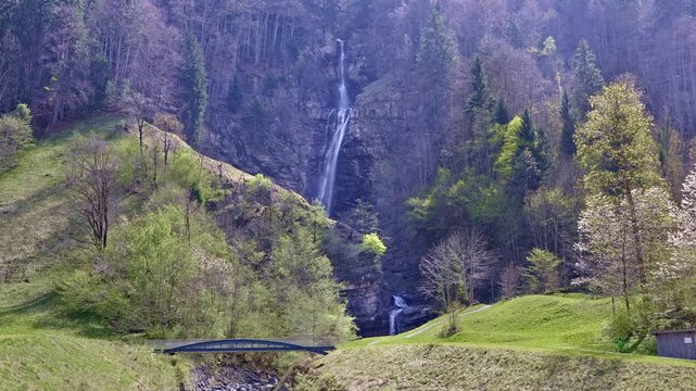A scenic multi-tiered waterfall on a mountain stream dropping from steep slopes into the valley. Diesbachfall waterfall, canton Glarus, Switzerland.