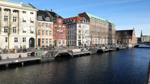 A view of historic buildings with large windows in the Danish capital. Tourists strolling. Historic street