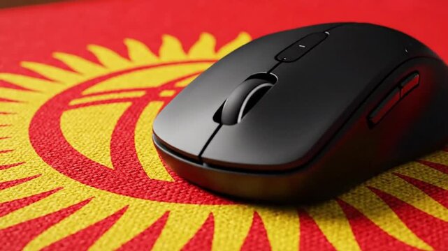 Black wireless computer mouse on a patterned red  yellow mousepad