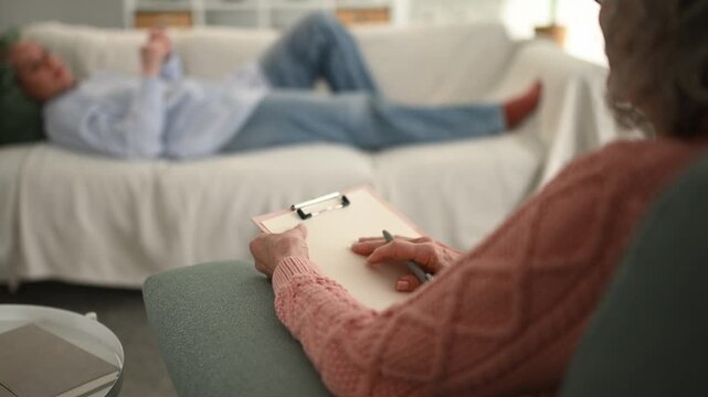 Psychotherapist listening to patient lying on the couch during session
