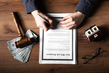 Woman signing Last Will and Testament at wooden table, top view