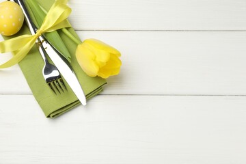 Easter table setting. Beautiful silverware with tulip and painted egg on white wooden background,...