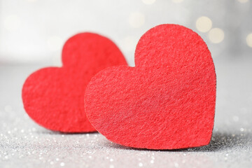 Love. Red decorative hearts on shiny gray surface against blurred background, closeup