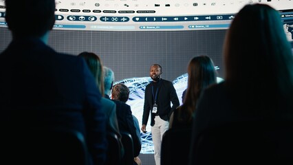 Black public speaker presenting turbine for industrial machinery on stage, mechanical equipment...