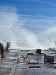 Fototapeta premium wave crashing on pier with blue sky, copyspace for banner, travel
