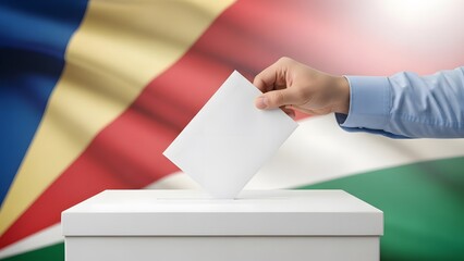 Obraz premium A person's hand places a ballot into a white election box, set against the vibrant national flag of Seychelles.