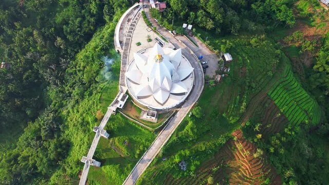 Aerial drone footage of Al Kamil mosque from above, with a lotus flower shape, the main square, a road, food stalls, a bridge, in Jatigede reservoir, Sumedang regency, Java island, Indonesia