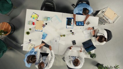 Top down view of diverse professionals collaborating in brainstorming session. Team shares medical expertise and diagnostic solutions for improved therapy at clinic. © DC Studio