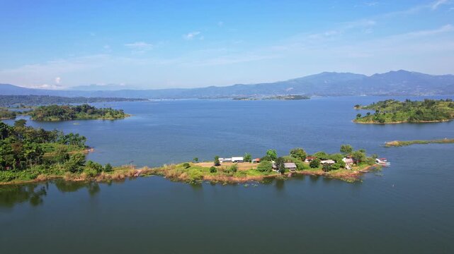 Aerial drone footage of a tiny thin peninsula, with some food stalls and fishing activity counters, with the whole Jatigede reservoir behind in flat waters, in Sumedang regency, Java, Indonesia