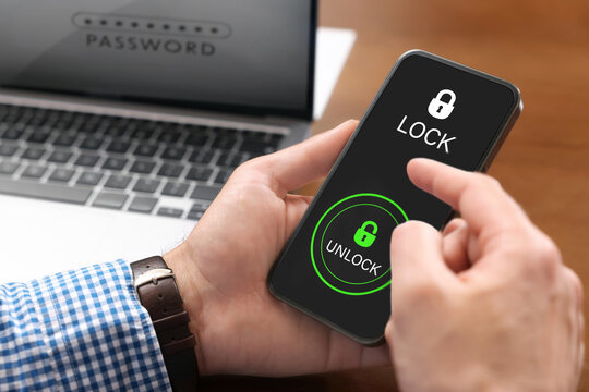 Privacy protection. Man signing into account with Password on laptop and unlocking mobile phone, closeup