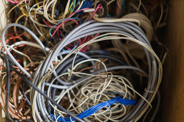 A chaotic tangle of multicolored wires and cables spills out of a container.