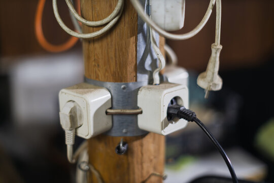 An extension cord and several power outlets are attached to a wooden pole.