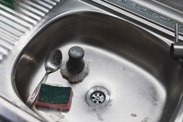 Obraz premium A kitchen sink with a sponge, spoon, and brush.