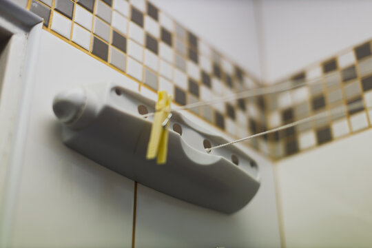 A retractable clothesline is mounted on a tiled wall in a bathroom.