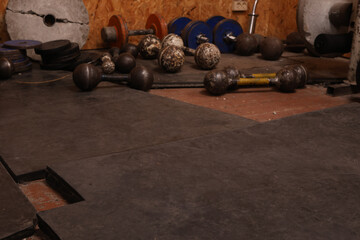 Fototapeta premium Vintage gym equipment including dumbbells and weight plates scattered on a rubber mat