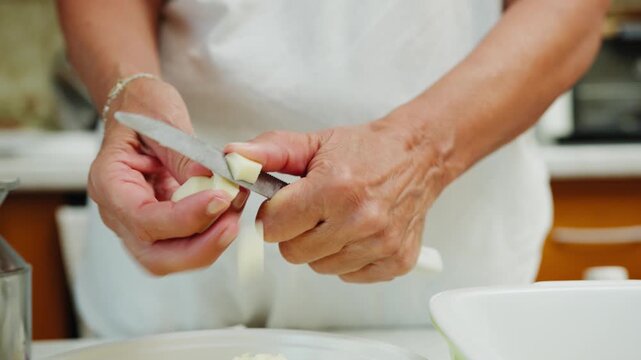 A womans hands cut provola cheese into pieces for Emilian lasagna