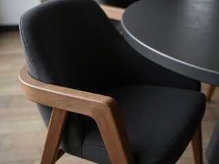 Modern Interior Armchair. A close-up view of a modern armchair with wooden armrests and a black fabric seat near a round table.